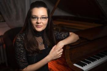 Pianist Katelyn Bouska sits beside a piano